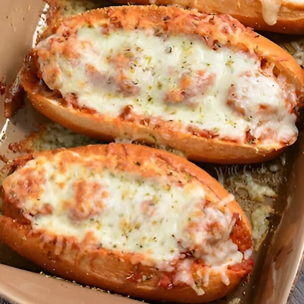 Two Devil's Pizzeria meatball subs, generously topped with melted mozzarella cheese and herbs.